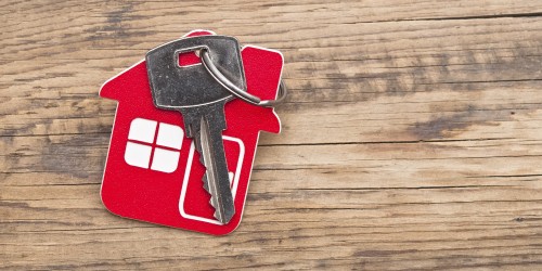 Symbol of the house with silver key on wooden background